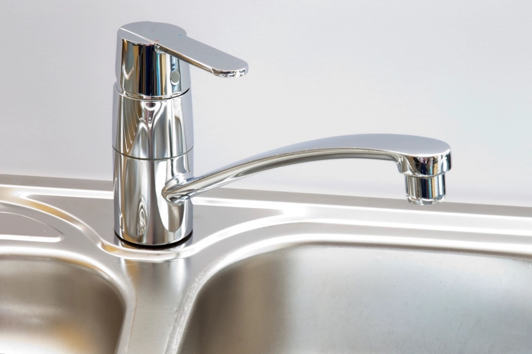 A chrome kitchen mixer tap on a stainless steel sink